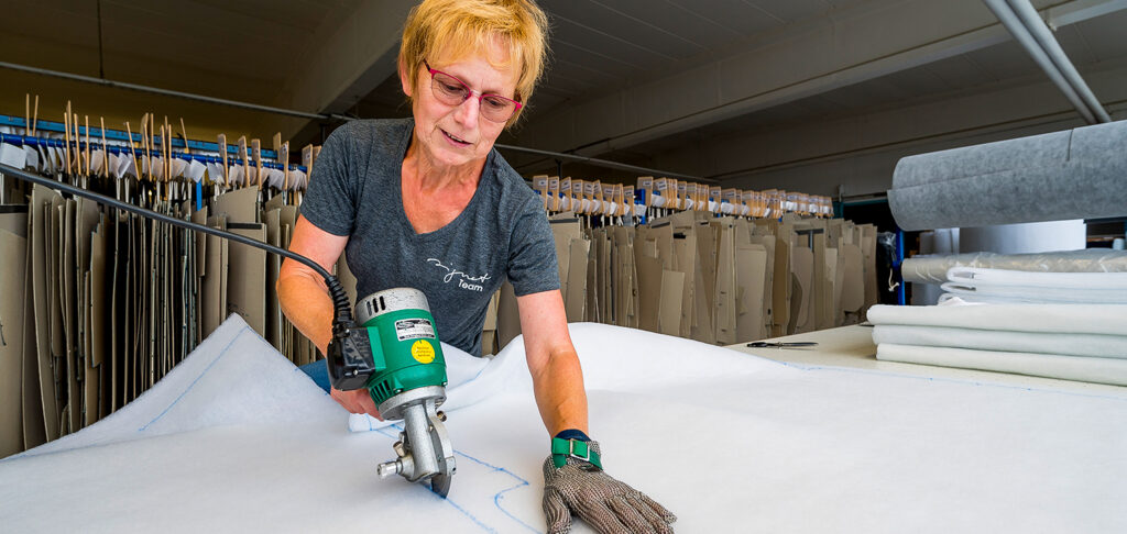 Eine Frau mit Brille schneidet eine Stoffbahn