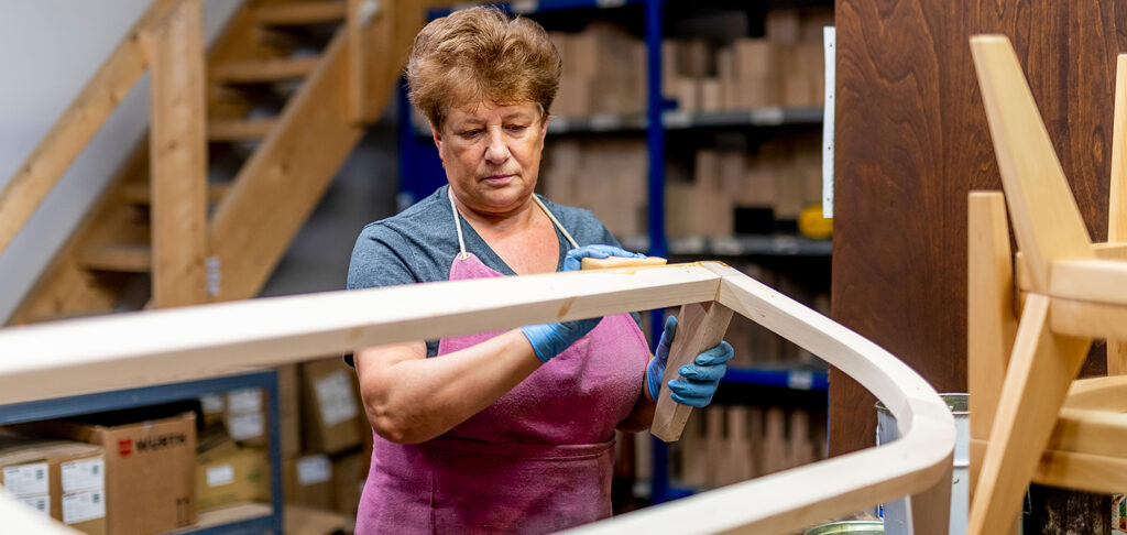 Eine Frau schmirgelt einen Holzlattenrost